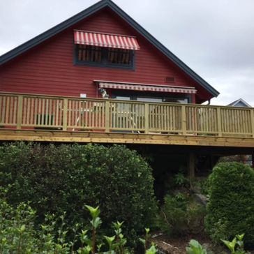 Ferdigstilt terrasse og rekkverk på rødt hus sett ovenifra med cirka 2 meter over bakken